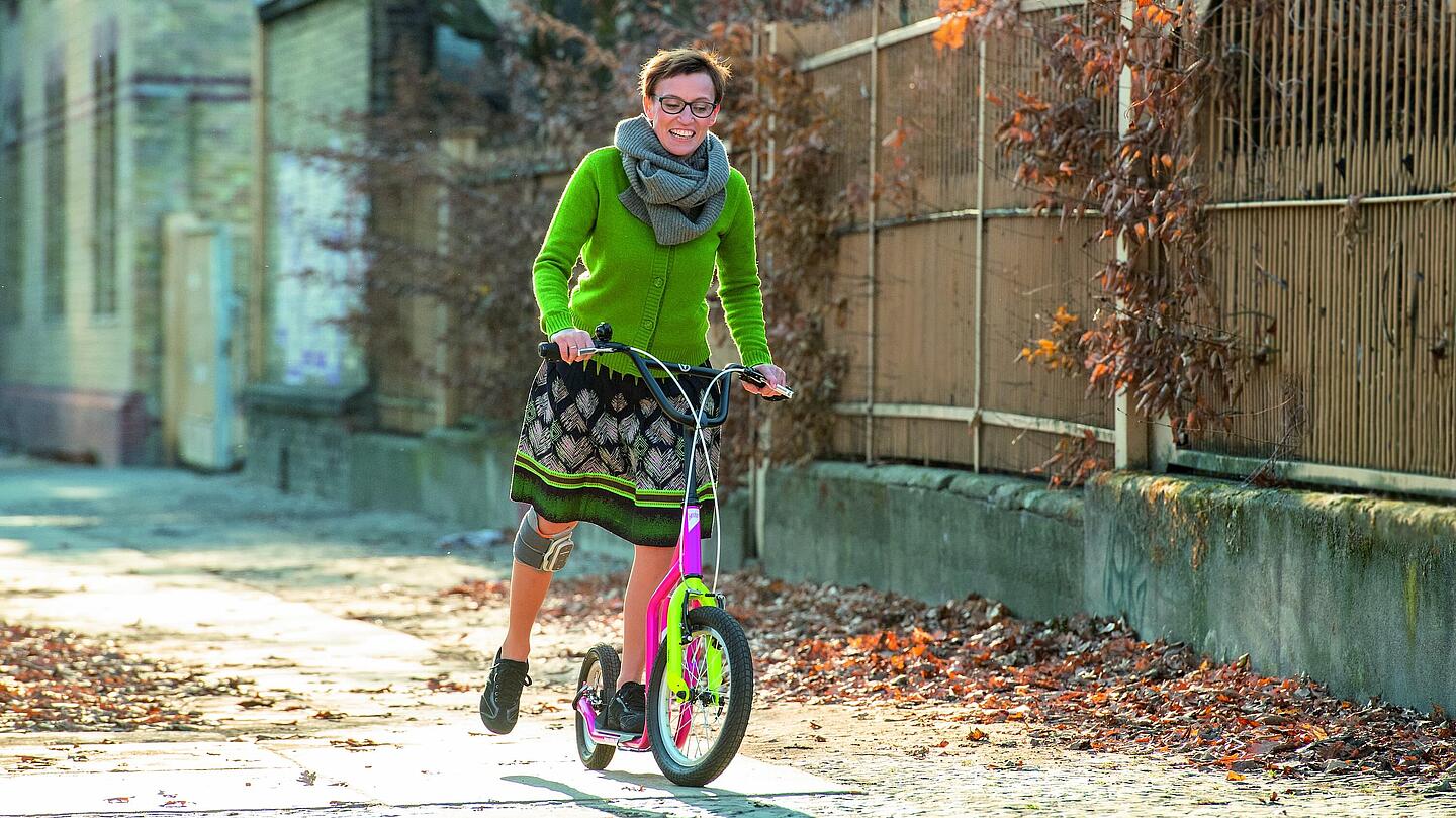 Frau mit Knie-Manschette, die Roller fährt, © Ottobock