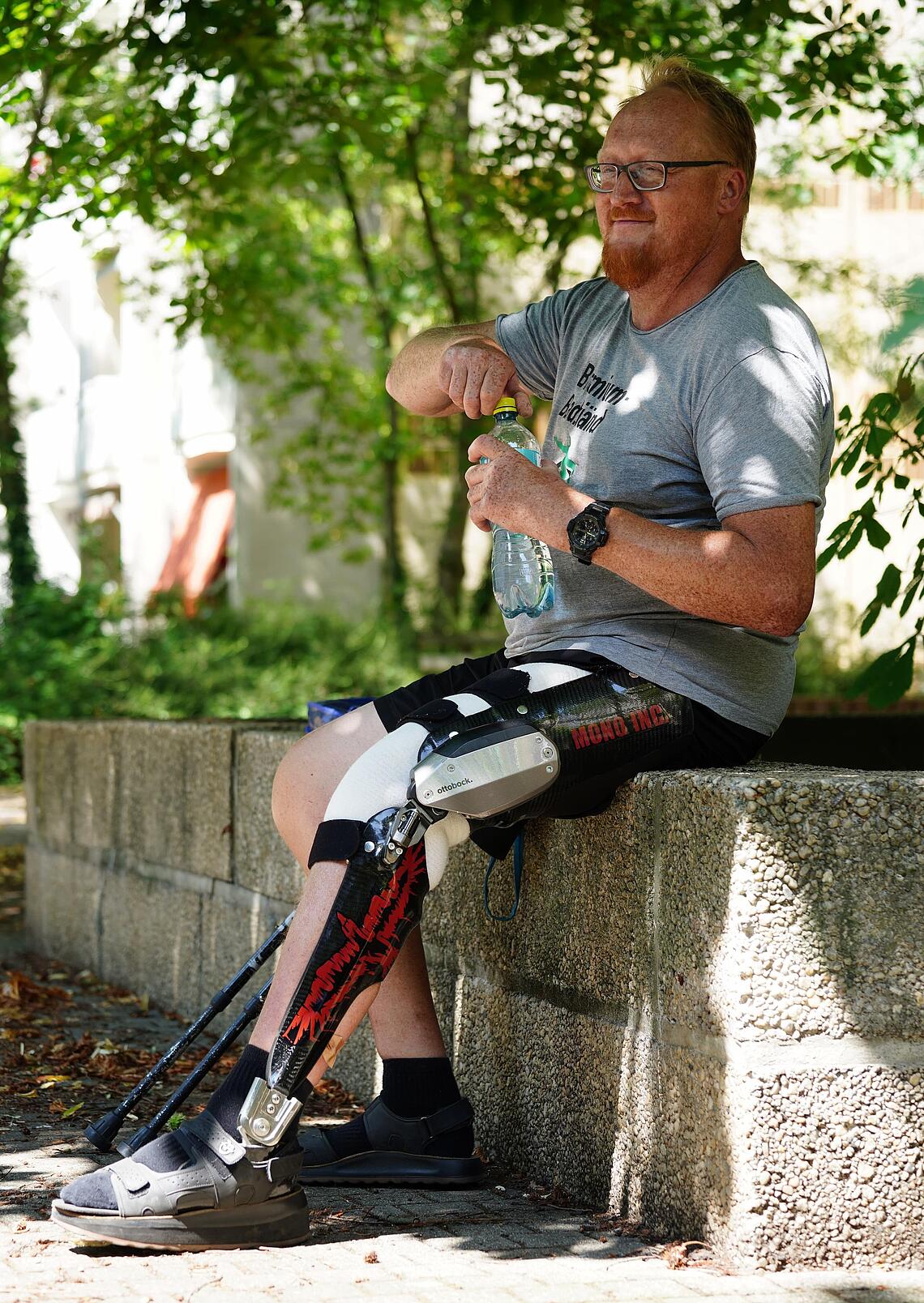 C-Brace-Anwender macht auf einer Steinmauer Pause und trinkt Wasser