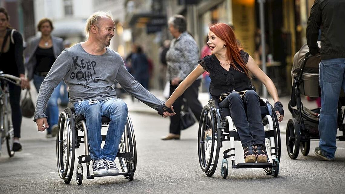 glückliches Paar aus Mann und Frau, die händehaltend im Rollstuhl sitzen, ©Invacare