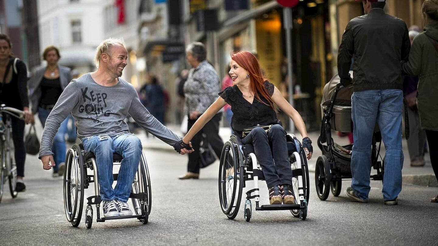 glückliches Paar aus Mann und Frau, die händehaltend im Rollstuhl sitzen, ©Invacare