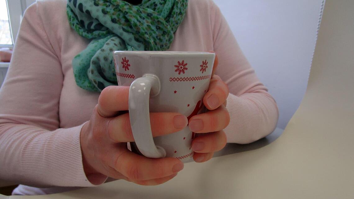 Hand mit Silikon-Fingerprothesen, die eine Tasse hält