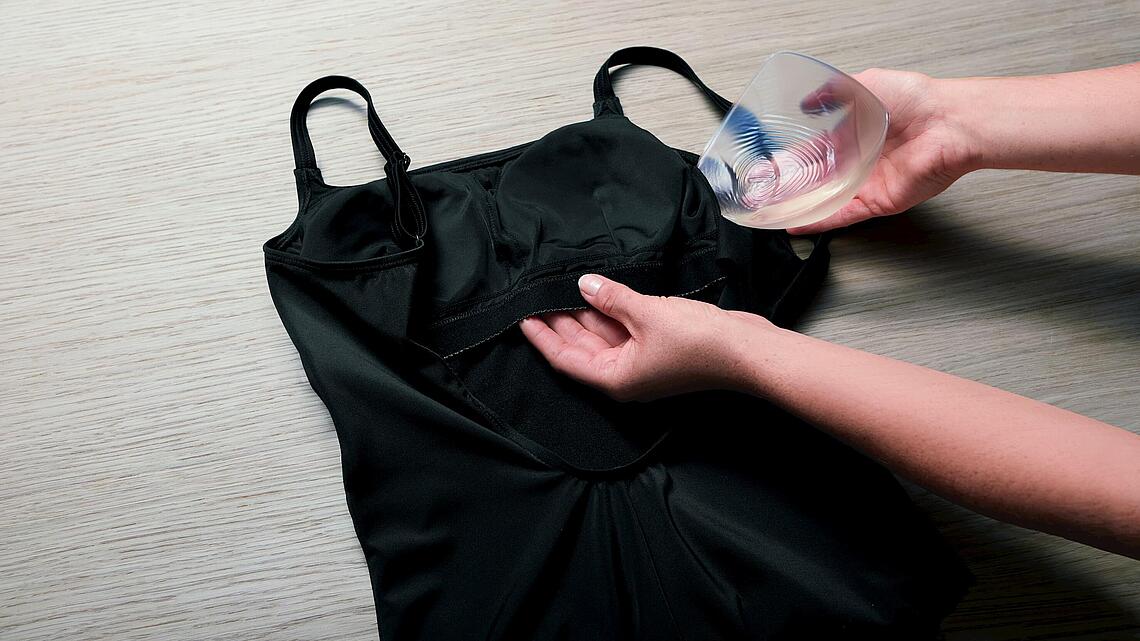 Epithese wird in den Brustbereich eines Badeanzugs eingefügt, Copyright: Amoena Medizin-Orthopaedie-Technik GmbH