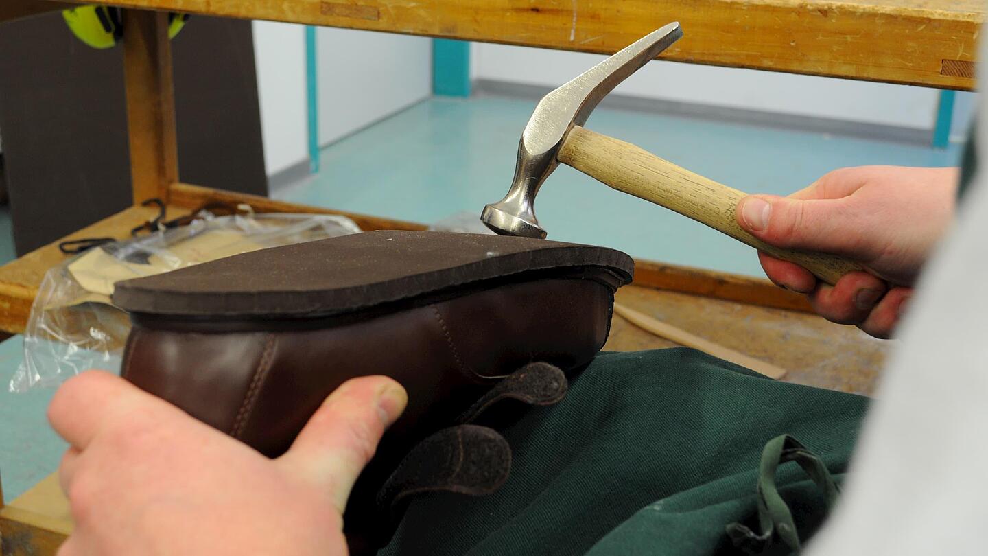 die Sohle des Schuhs wird zur Befestigung mit dem Hammer bearbeitet