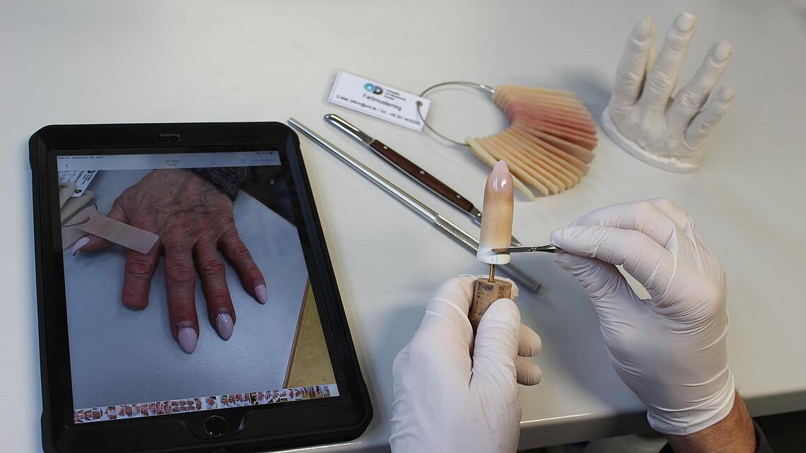Airbrush-Arbeiten an Fingerprothese mit Bildvorlage der realen Hand