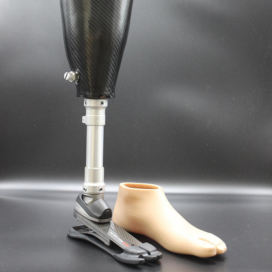 Unterschenkelprothese mit Spezialfuß für unebene Untergründe, daneben steht der kosmetische Überzug