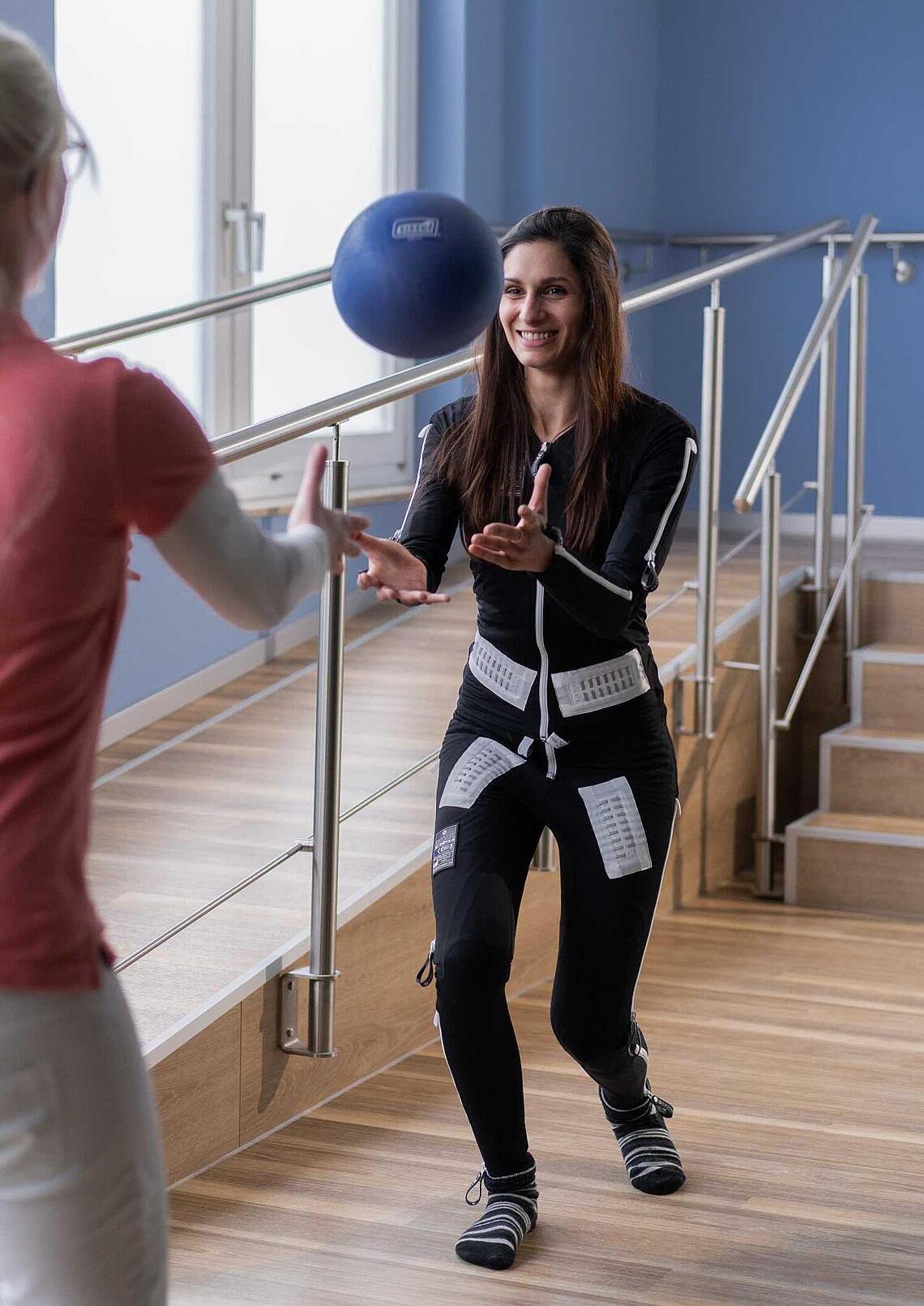 Frau mit EXOPULSE Mollii Suit beim Ballspielen, © Ottobock Frau mit EXOPULSE Mollii Suit wirft einen Ball zu einer anderen Frau, © Ottobock