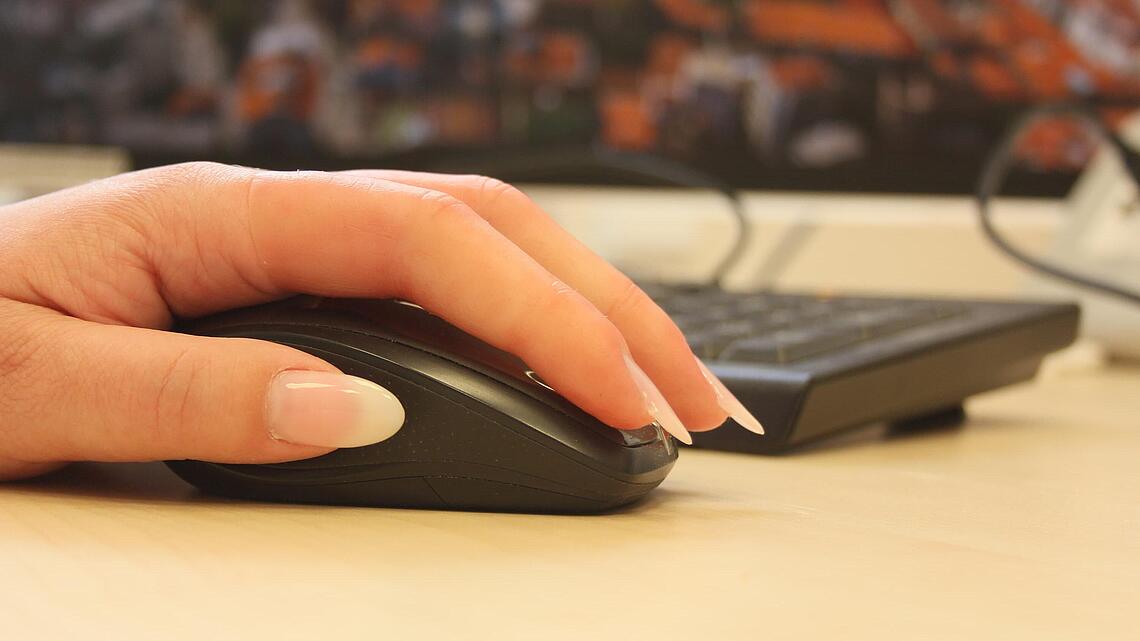 Hand mit zwei Fingerprothesen aus Silikon auf einer Computer-Maus
